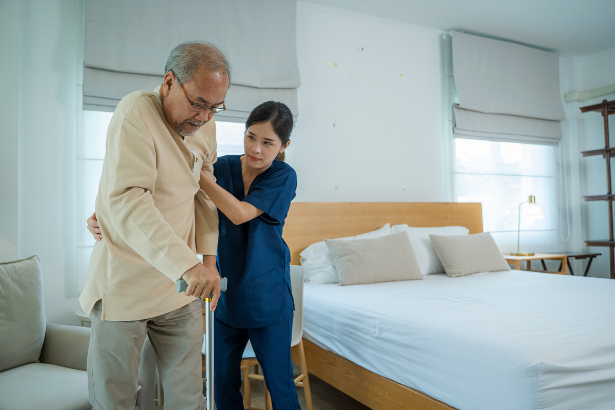 Nurse helps senior man practice walking at nursing home,Caregive
